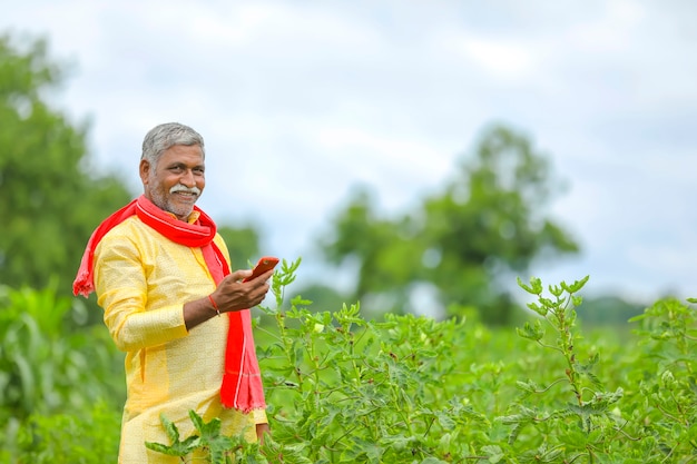 Agricoltore indiano utilizzando il telefono cellulare al campo agricolo