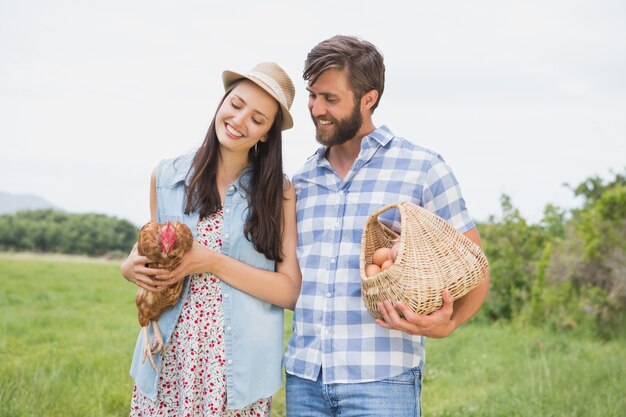 Agricoltori felici che tengono pollo e uova