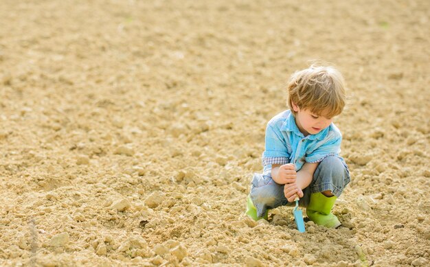 Agricoltura e agricoltura ragazzino piantare un fiore ecologia e protezione ambientale giornata della terra nuova vita estate fattoria bambino felice giardiniere operaio botanico Primavera Godersi il lavoro con le piante