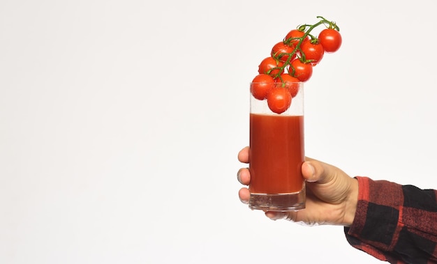 Agricoltura e autunno La mano maschile tiene un bicchiere di succo di pomodoro