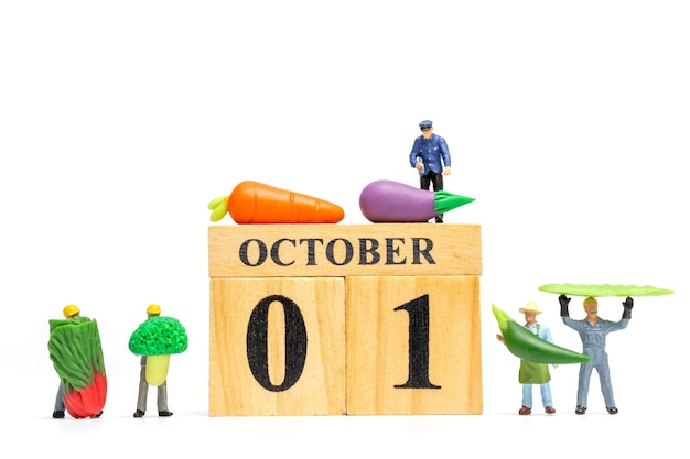 Agricoltura miniatura della gente che lavora al calendario di legno 1 ottobre su fondo bianco. Concetto di Giornata mondiale vegetariana