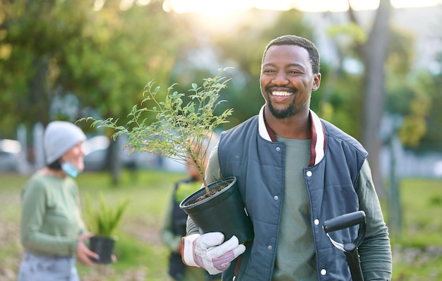 Agricoltura natura e uomo nero con una pianta in un parco dopo aver fatto giardinaggio sostenibile Sorriso felice e giardiniere maschio africano ecologico in piedi con verde sul campo all'aperto in campagna
