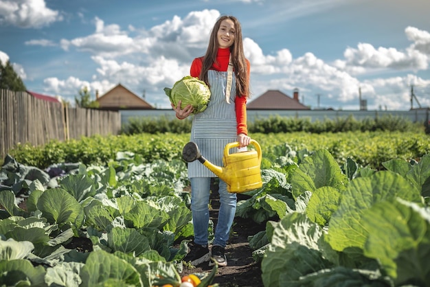 Agronomo agricoltore femmina irriga le piante da un annaffiatoio giallo nel suo giardino La gioia di prendersi cura della propria fattoria