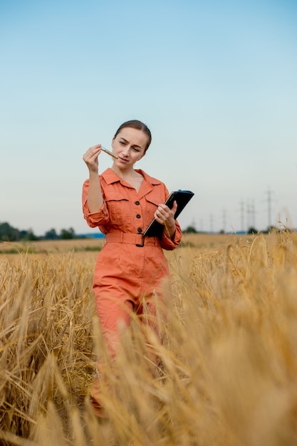 Agronomo tecnologo caucasico donna con computer tablet nel campo del grano che controlla la qualità e la crescita delle colture per l'agricoltura. Agricoltura e concetto di raccolta.