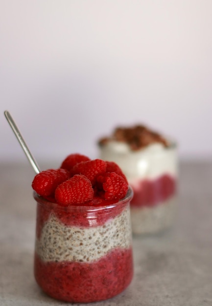 Ai bicchieri di budino di chia con yogurt e lampone su un tavolo di marmo grigio