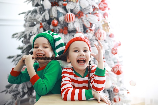 Aiutanti di Babbo Natale. Bambini carini in costumi da elfo di Natale in una stanza splendidamente decorata per Natale. Tempo di miracoli. Regali di Babbo Natale.