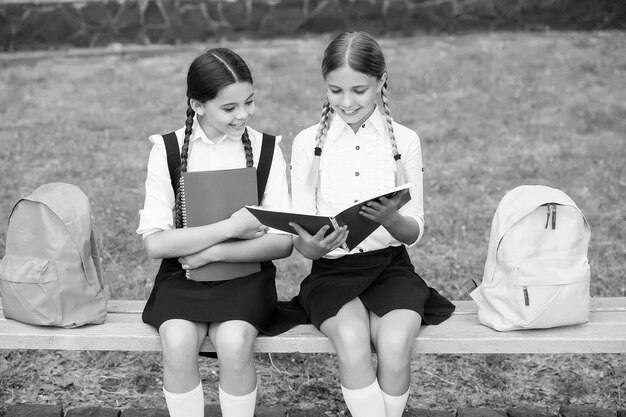 Aiutare e supportare i bambini a leggere il quaderno per prendere appunti infanzia felice torna a scuola gli alunni adolescenti pronti per la lezione prepararsi per l'esame studiare insieme all'aperto bambine con libri e zaini