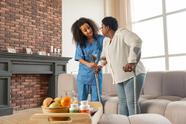 Aiutare la donna. Aiutare il giovane assistente medico dell'ospedale ad aiutare la donna a camminare con le stampelle