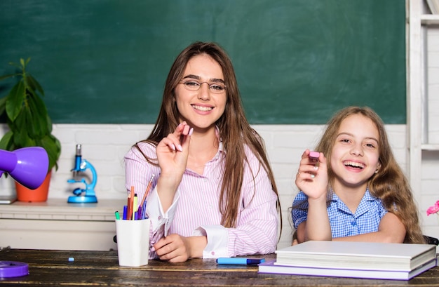 Aiuto con i compiti Progetto compiti Sorella che aiuta con l'apprendimento Insegnante gentile signora con allievo Fare i compiti con la mamma Bambina e donna si siedono alla scrivania Istruzione scolastica Studiare insieme