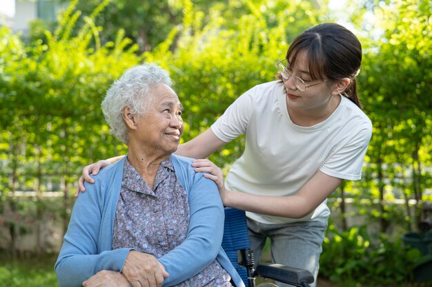Aiuto e cura del caregiver donna anziana asiatica usa un camminatore con una buona salute mentre cammina nel parco in una vacanza felice e fresca