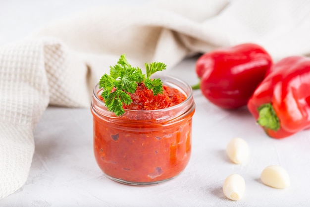 Ajvar di peperoni rossi pomodori aglio e cipolle con spezie e verdure in un barattolo di vetro sul tavolo