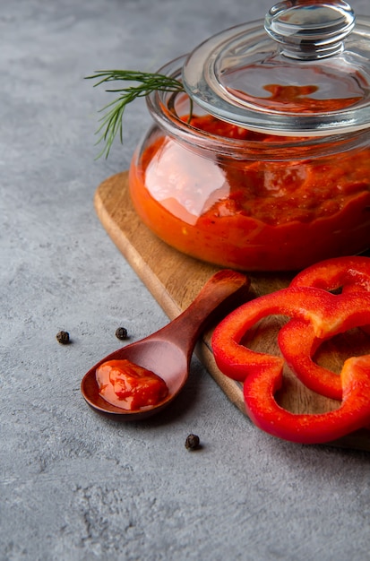 Ajvar in un barattolo di vetro su uno spazio grigio