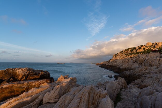 Al mattino il sole splende sugli scogli e sulle onde della spiaggia;