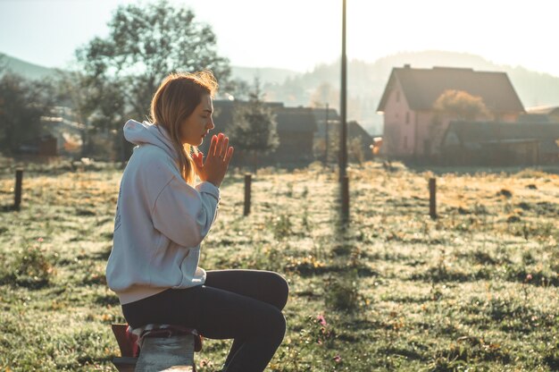 Al mattino la ragazza chiuse gli occhi, pregando all'aperto, le mani giunte nel concetto di preghiera per la fede, la spiritualità e la religione. Pace, speranza, concetto di sogni.