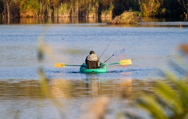 Al mattino presto un pescatore si siede su una barca in mezzo al lago e cattura il pesce