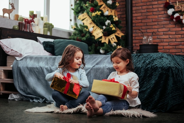 Al momento prima dell'apertura dei regali. Vacanze di Natale con regali per questi due bambini che stanno in casa nella simpatica stanzetta vicino al letto.