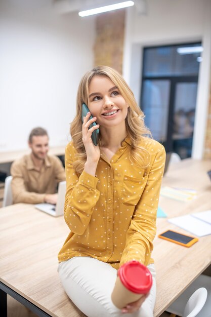 Al telefono. Giovane bella ragazza bionda in ufficio a parlare al telefono