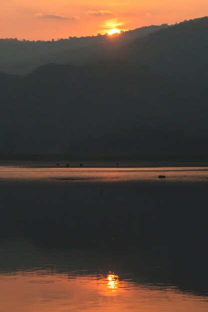 Al tramonto paesaggio di montagna di riflessione lago silhouette. Sole che tramonta dietro le montagne. Tramonto sulla montagna.