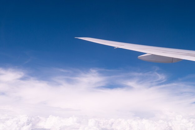 Ala dell&#39;aeroplano sulla nuvola e sul chiaro cielo blu per il concetto di viaggio di turismo