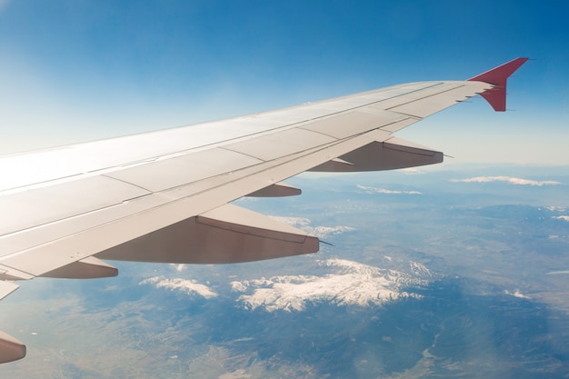 Ala di aereo sulle nuvole, mosche sulle montagne