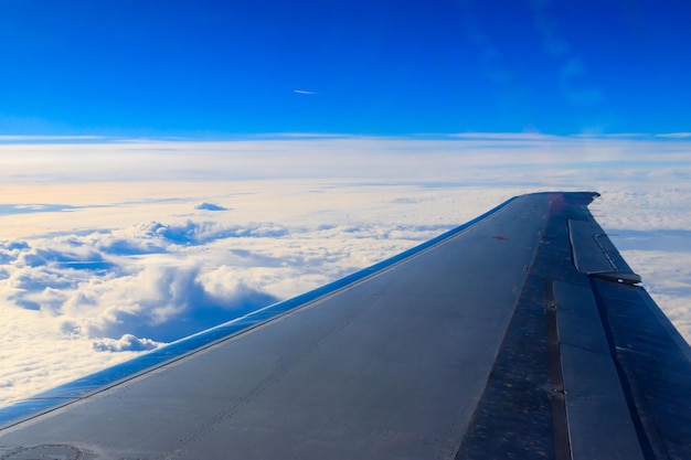 Ala di aeroplano che vola sopra le nuvole nel cielo blu