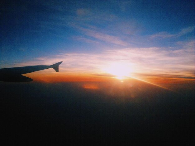 Ala di un aereo contro il cielo durante il tramonto
