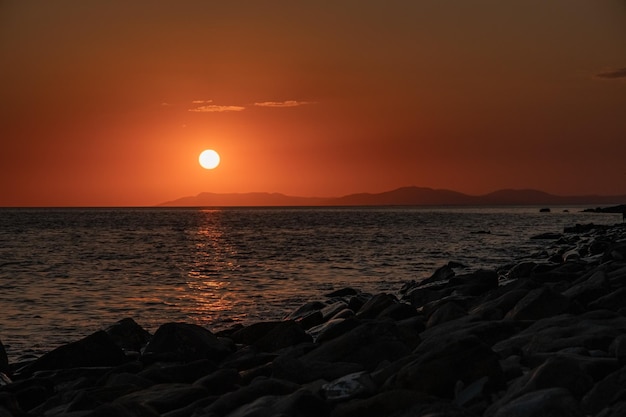 Alba al mattino sul mare che brilla di luci cremisi sulla superficie dell'acqua del cielo e del mare con un uccello