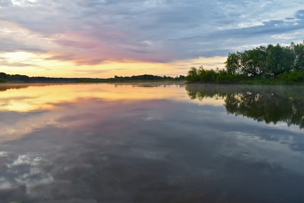 Alba colorata e nebbiosa su un piccolo fiume