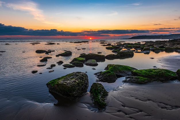 Alba colorata sulla costa rocciosa