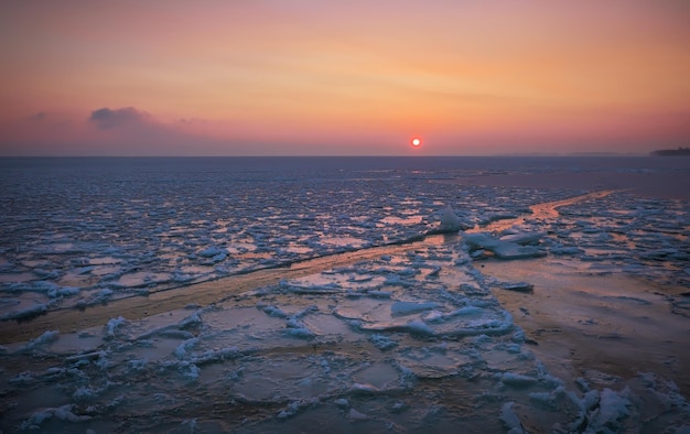 Alba e mare ghiacciato Bellissimo paesaggio invernale con lago e sole rosso al mattino Alba