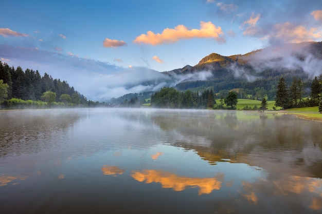 Alba nebbiosa sul lago con belle nuvole e riflessione Freizeitsee Zenz Austria Europa