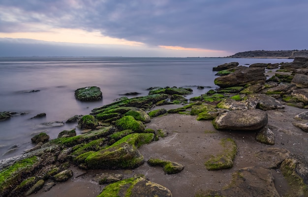 Alba nuvolosa sulla costa rocciosa del mare, lunga esposizione