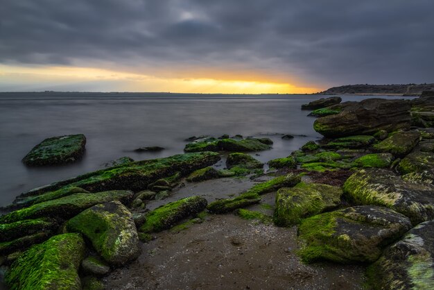 Alba nuvolosa sulla costa rocciosa del mare, lunga esposizione