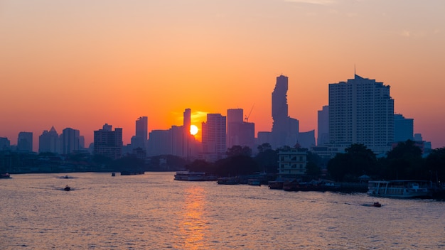 Alba sopra l'orizzonte scenico a Bangkok, Tailandia, osservata in controluce ad alba con il chiaro cielo rosso arancio.