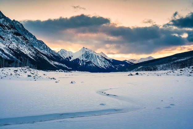 Alba sul lago Medicine con montagne rocciose e lago ghiacciato nel parco nazionale di Jasper