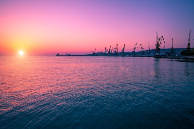 Alba sulla spiaggia di pietra con porto