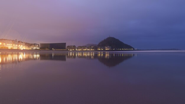 Alba sulla spiaggia di Zurriola Luci della città all'alba sulla spiaggia di Zurriola Donostia San Sebastian