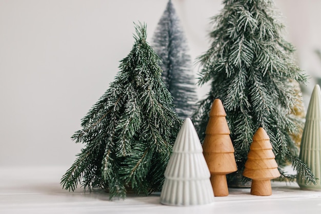 Alberelli di Natale su sfondo bianco Foresta invernale arredamento moderno festivo Buone vacanze Ceramica in miniatura Legno di pino innevato e fatto a mano Auguri di buon Natale Buon Natale
