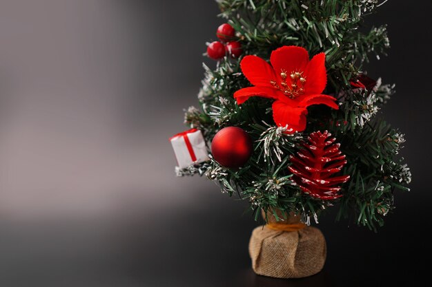 Albero artificiale decorato di Natale e Capodanno con palline rosse e giocattoli su sfondo nero