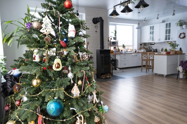 Albero di Natale all'interno bianco di una casa con grandi finestre Lucine incandescenti ghirlande decorazione interna della sala studio Piante in vaso in casa