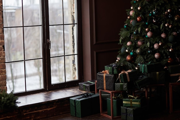 Albero di Natale all'interno della casa vicino alla grande finestra in chiave alta Presenta la casella vicino all'albero decorato