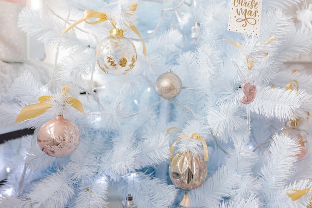 Albero di Natale bianco decorato con palline di Natale rosa dorato argento e bellissime palline di vetro su ramo blu bianco scintillante e fata, luci decorative, spazio copia. Foto.