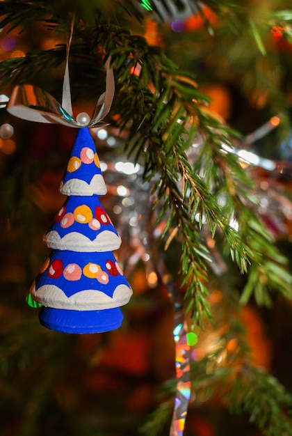 Albero di Natale brillantemente colorato di legno del giocattolo di Natale che appende sul ramo attillato verde.