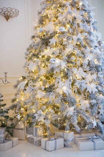 Albero di Natale con decorazioni bianche e argento scatole regalo e ghirlanda di luci White Christmas concept Casa accogliente con decorazioni natalizie