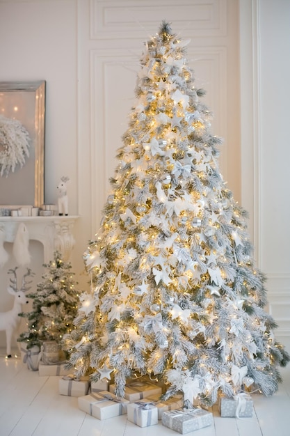 Albero di Natale con decorazioni bianche e argento scatole regalo e ghirlanda di luci White Christmas concept Casa accogliente con decorazioni natalizie