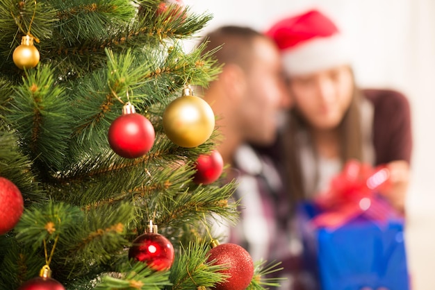 Albero di Natale con decorazioni natalizie. Concentrarsi in primo piano. Lo sfondo è una coppia di Buon Natale.