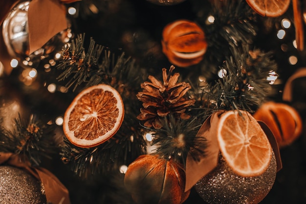 Albero di Natale creativo decorato con arance secche e pigne Dettagli accoglienti e bokeh dorato