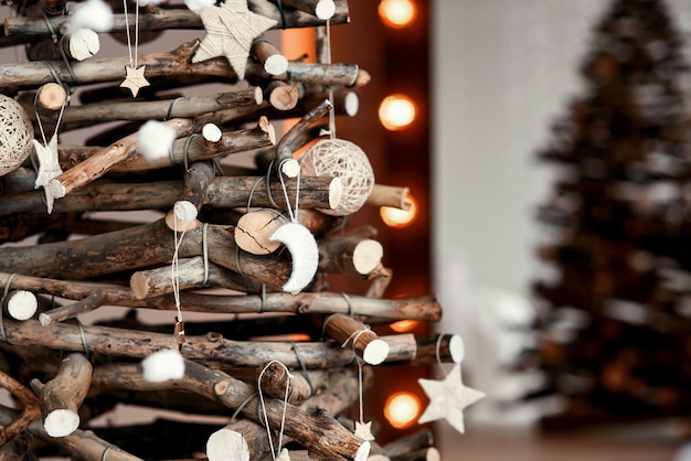 Albero di Natale decorativo in legno con giocattoli fatti a mano. Elegante interno di Natale decorato in stile rustico.