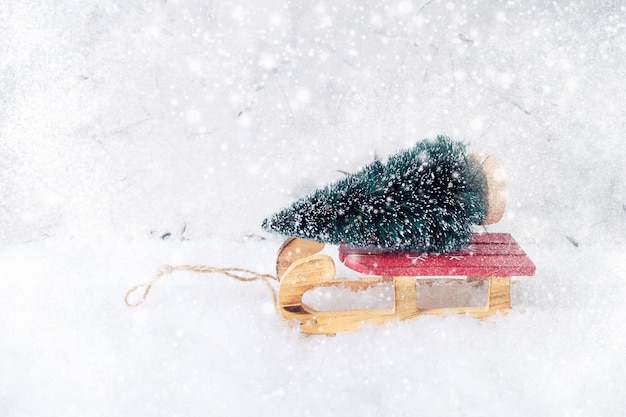 Albero di Natale decorativo sulla slitta rossa. Trama di neve, copia spazio. Biglietto d&#39;auguri.