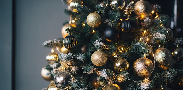 Albero di Natale decorato con ghirlande e palline dorate su una parete scura